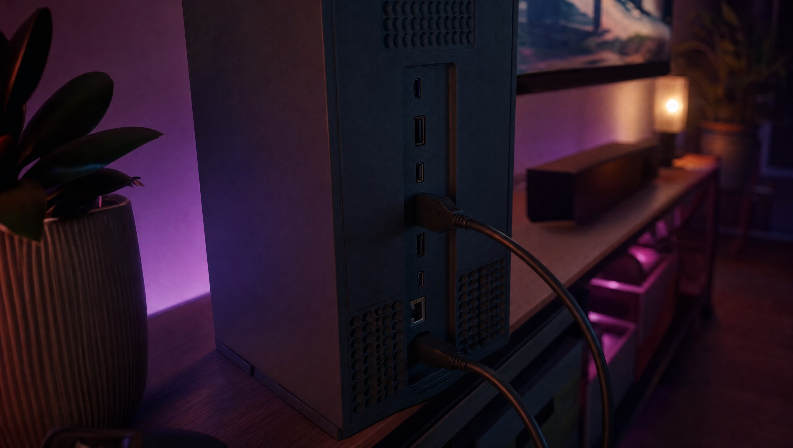 The rear panel of an upright console in shadow, ports in a row, two cables seated.
