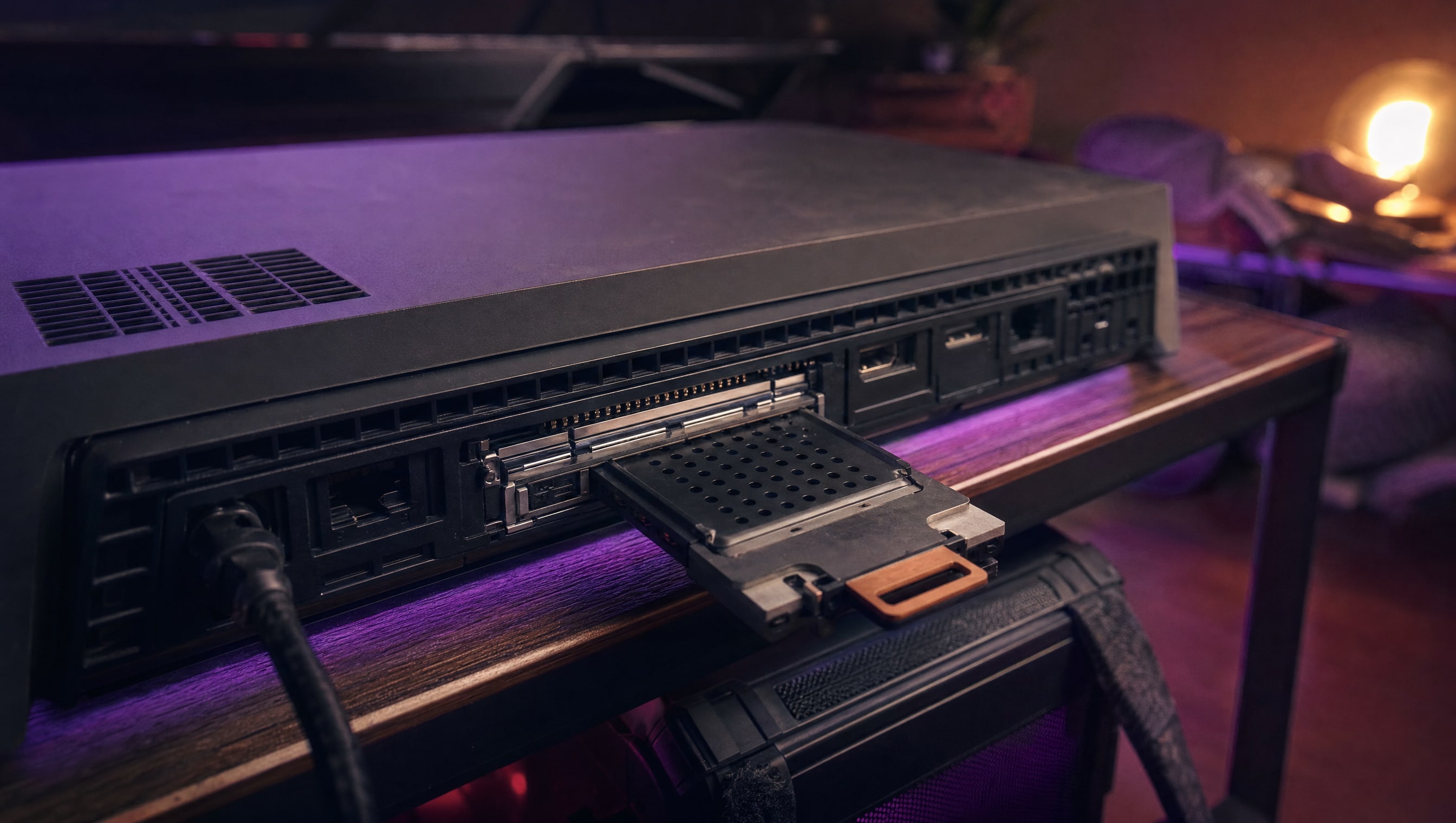 A storage expansion card being slid into a bay on the back of a flat console.