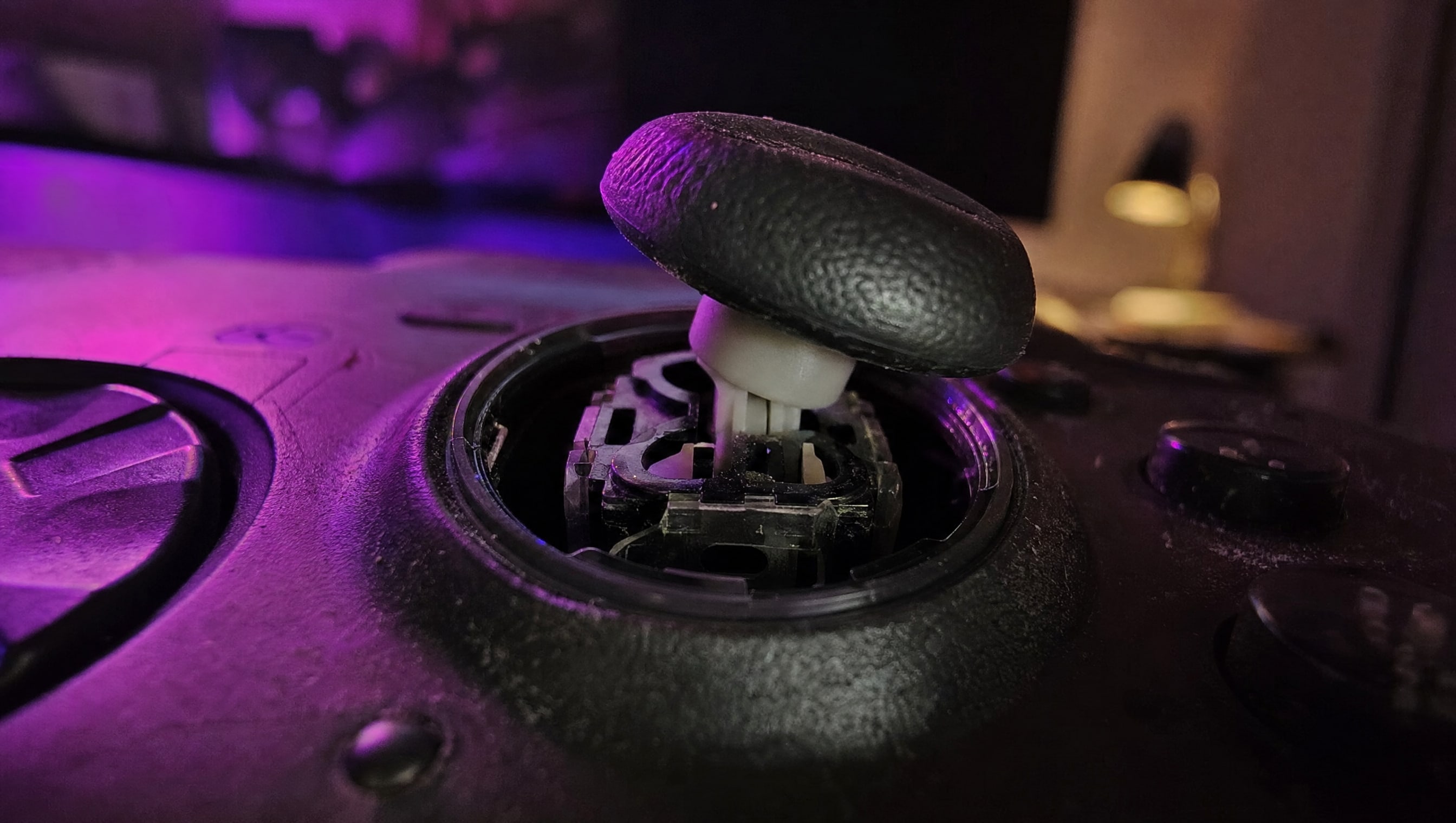 Extreme macro on a thumbstick pushed to one side, the gap around its collar wide open and lit.