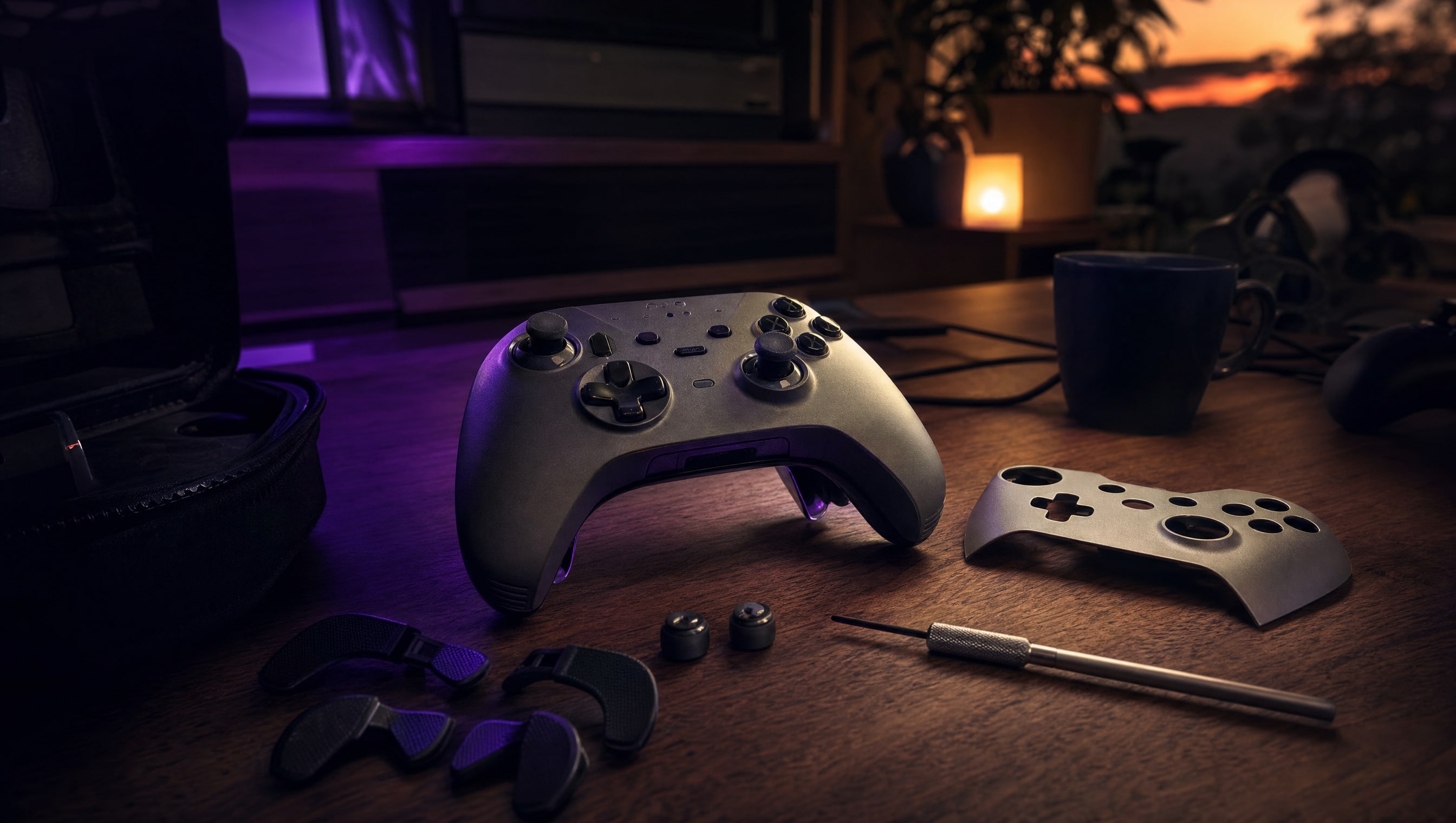A desk at night: a controller, a spare faceplate, a paddle kit and a small screwdriver.