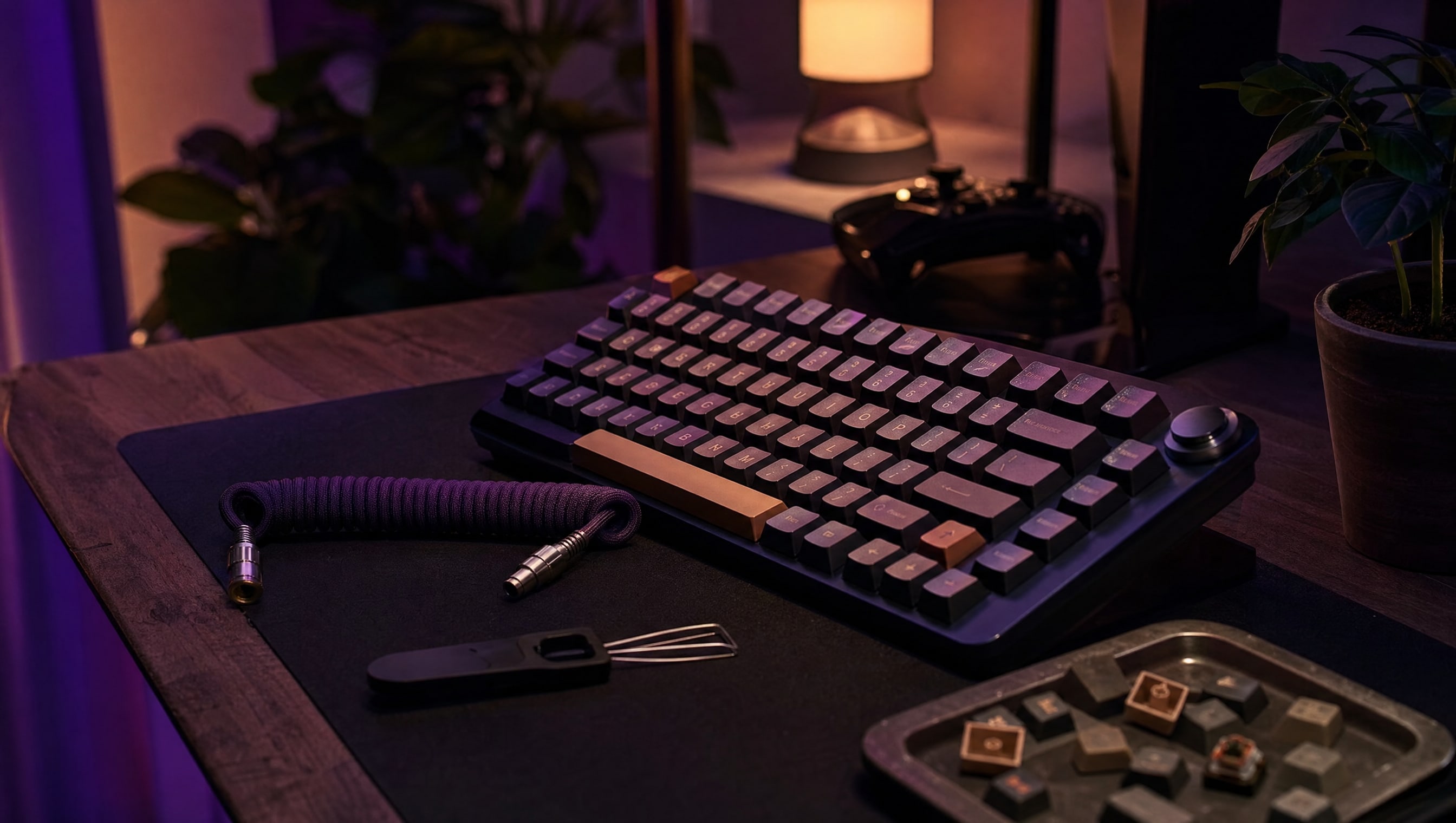 A desk at night: a keyboard, a coiled cable, a keycap puller and a tray of spare caps.