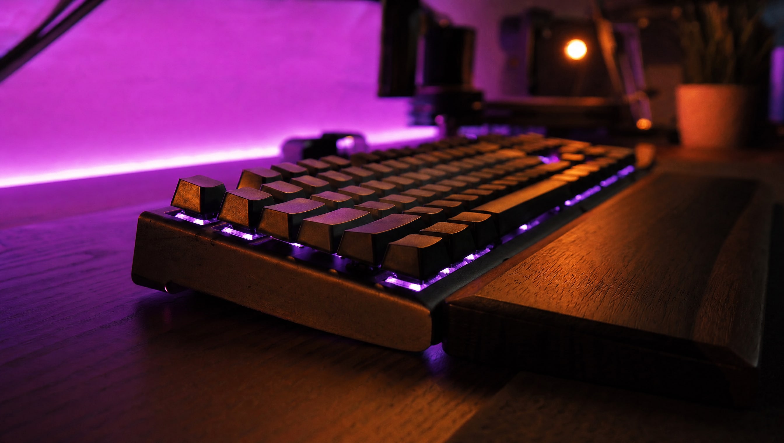 A mechanical keyboard from a low grazing angle so the key rows recede, violet strip light behind.