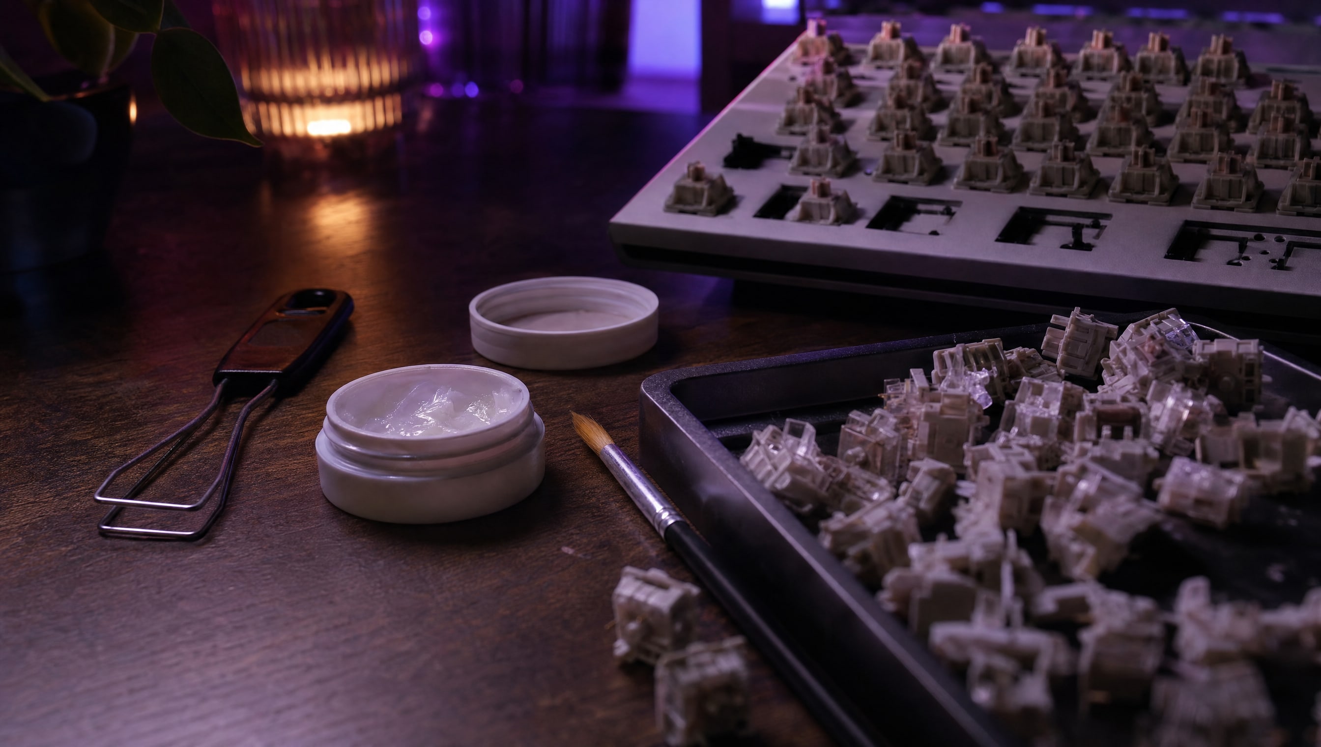 A desk at night: a switch puller, lubricant, a fine brush and a tray of switch halves.