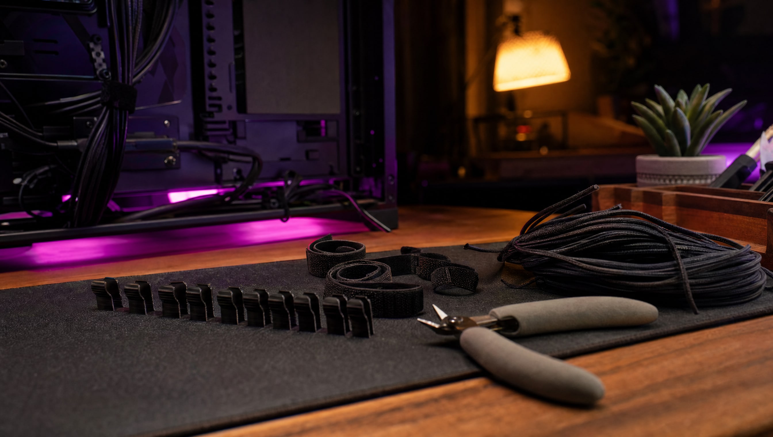 A desk at night: velcro ties, a cable comb, snips and a coil of unused cable.