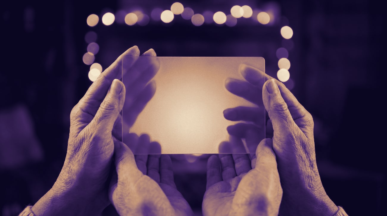 A pair of hands holding a single lit page up to the light.