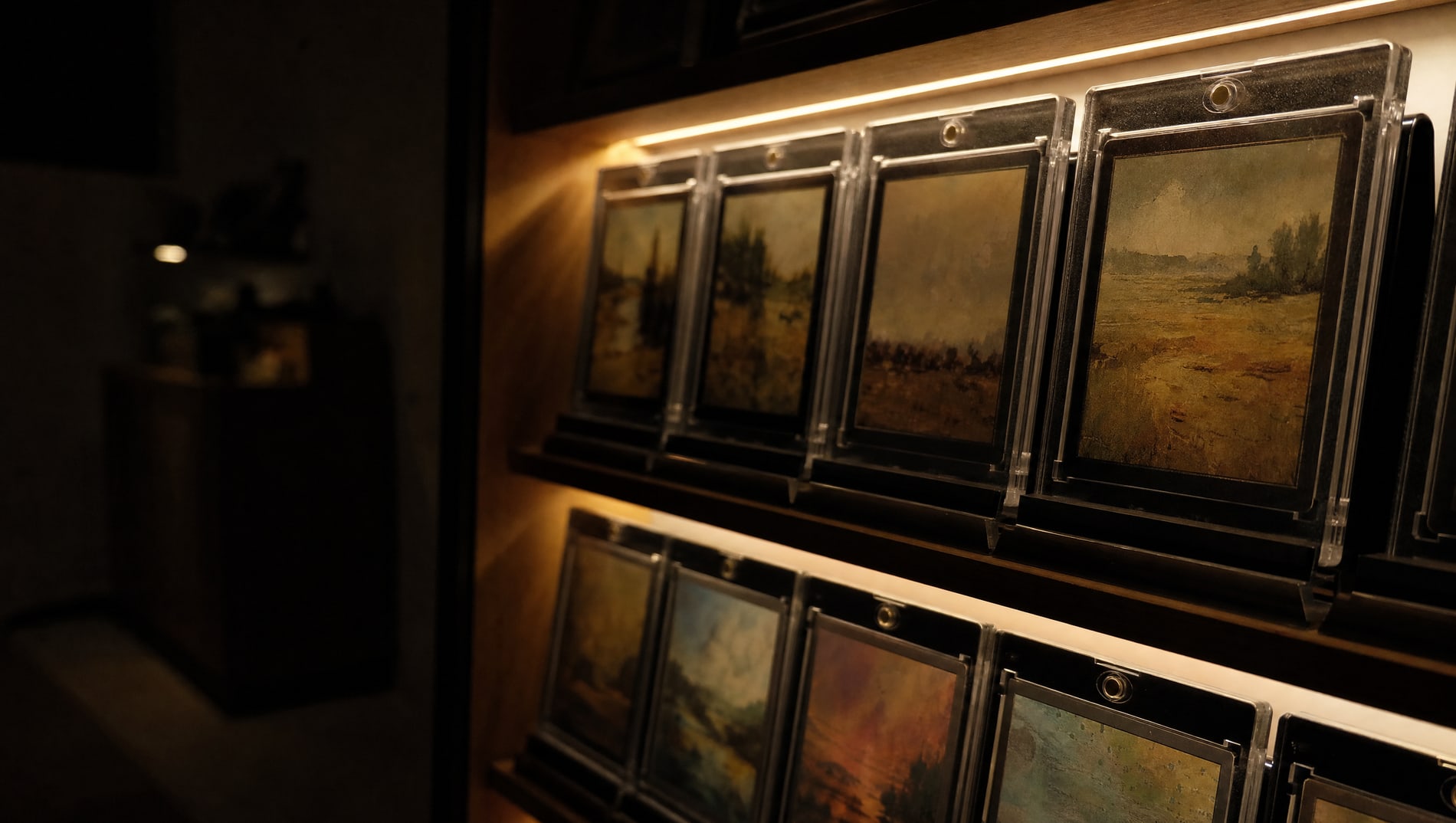 A dim room with one small lit display shelf of slabbed cards, the rest of the room in darkness.